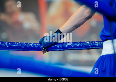 Homme boxer en corner ring de boxe, la main avec serrage sur cordes bleu Banque D'Images