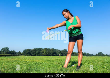 Femme colombienne servir avec raquette de badminton et de navette à l'extérieur dans l'herbe Banque D'Images