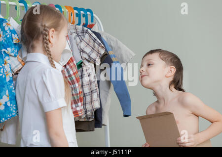 Deux petits enfants près d'un cintre à vêtements à la maison au moment de la journée. Les enfants s'amusant à l'intérieur. Banque D'Images