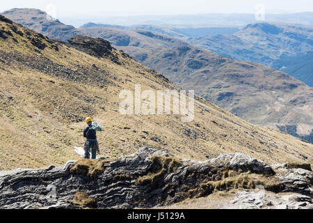 Un alpiniste atteint le sommet des falaises sur Ben Artair, "le cordonnier", un populaire pour l'escalade de montagne dans l'ouest des Highlands d'Écosse. Banque D'Images