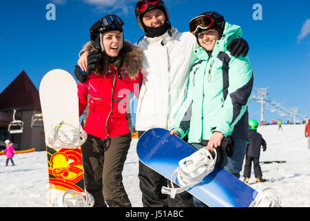 Les jeunes gens heureux dans les combinaisons de ski, casques et lunettes de ski debout avec snowboards Banque D'Images