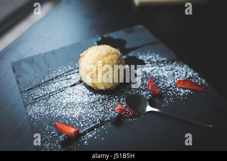 Grillades de la glace dans la noix de coco avec sauce sur la plaque en pierre noire. Arrière-plan de l'alimentation asiatique. Concept de l'alimentation. Restaurant place avec table en bois. L'espace de copie de texte, de la conception. Banque D'Images