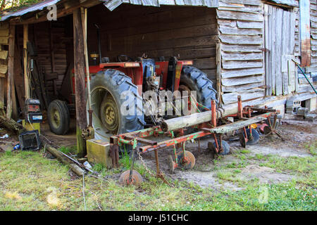 Tracteur avec charrue herse à disques dans une grange délabrée Banque D'Images