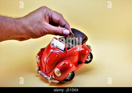 Coin bank. Man putting coins en coin bank. Coin bank enfant en forme de voiture symbolisant les économies pour acheter une nouvelle voiture. Banque D'Images