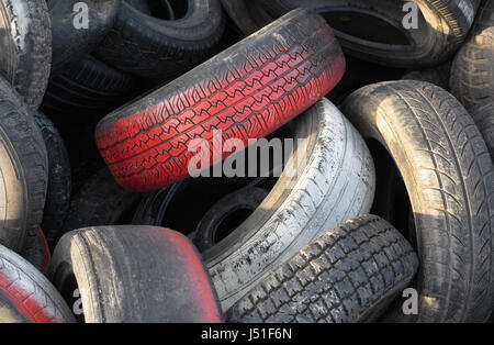 Close up de voiture rouge avec la bande de roulement des pneus dans une pile de pneus usagés Banque D'Images