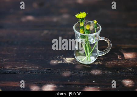 Bouquet de pissenlits jaunes en verre sur bois grunge Banque D'Images