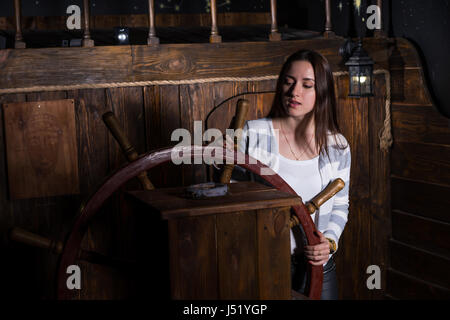Une jeune femme se tient à la barre du navire et s'intéresse à la boussole, concept de jeu échapper à la chambre Banque D'Images