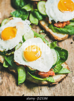 Petit-déjeuner sain des sandwichs. Toasts de pain frit avec des oeufs et des légumes sur planche de bois rustique background, selective focus. L'alimentation saine, propre à guérir Banque D'Images