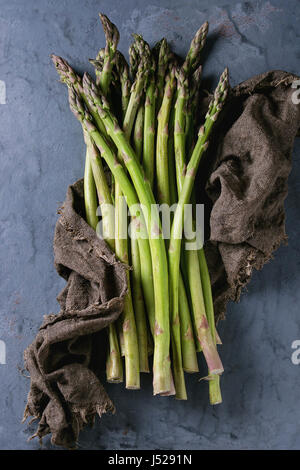 Ensemble de jeunes matières organiques non cuit asperges vertes sur le sac chiffon sur gris bleu metal texture background. Vue d'en haut. La saine alimentation Banque D'Images