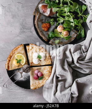 Variété de crêpes crêpe noir et blanc avec différents sweet et le sel le remplissage. Caviar rouge, poisson pate, jambon, salade verte, framboise, lait caillé de citron, mas Banque D'Images