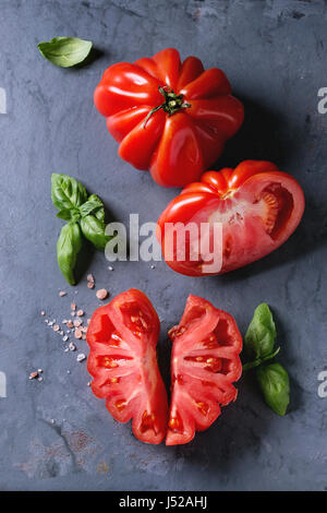 Ensemble et les tranches de tomates Coeur de boeuf bio. Émincé de Tomates avec basilic et sel rose sur gris bleu metal texture background. Vue de dessus avec l'espace Banque D'Images