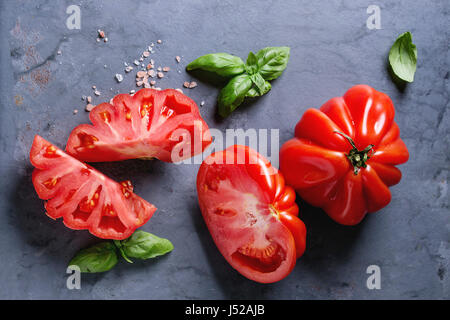 Ensemble et les tranches de tomates Coeur de boeuf bio. Émincé de Tomates avec basilic et sel rose sur gris bleu metal texture background. Vue de dessus avec l'espace Banque D'Images