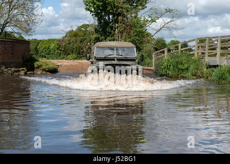 Parution du modèle de droit d'un homme conduisant une armée ex 1973 Land Rover Série 3 à empattement long dans la rivière VER qui forme une Ford à Redbournbury, Herts. Banque D'Images