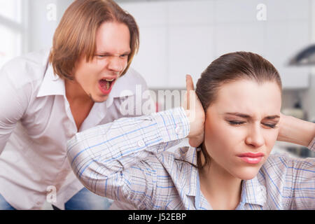 L'homme en colère crie à la jeune femme. Femme couvrant ses oreilles avec ses mains Banque D'Images