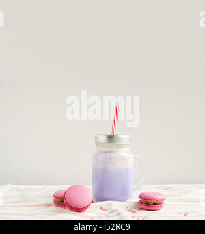 Café pourpre en pot Mason Tasse stylisée avec ses macarons et une décoration colorée. Lait frappé aux bleuets, cocktaill, frappuccino. Café Unicorn. Licorne f Banque D'Images