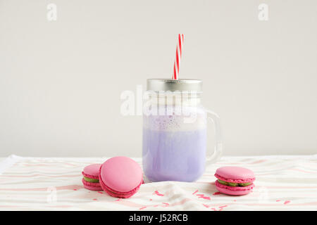 Café pourpre en pot Mason Tasse stylisée avec ses macarons et une décoration colorée. Lait frappé aux bleuets, cocktaill, frappuccino. Café Unicorn. Licorne f Banque D'Images