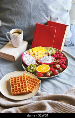 Petit-déjeuner au lit avec des gaufres belges, fruits frais et café Banque D'Images