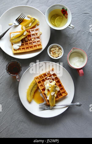 Gaufres aux bananes caramélisées, des yaourts et des flocons d'amandes grillées.vue d'en haut Banque D'Images