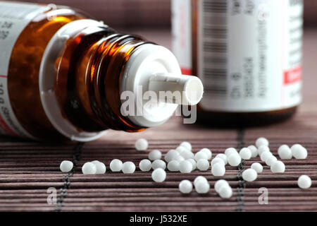 Pilules homéopathiques éparpillées tomber hors du flacon bouleversé Banque D'Images