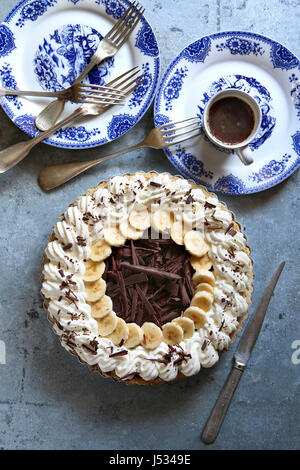 Tarte à la crème de banane au chocolat sur une casserole avec assiettes et couverts bleu.vue d'en haut Banque D'Images