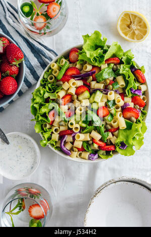 Salade de fraises avec des herbes et de concombre dans un bol et accompagné de deux verre d'eau aromatisée et bols. Banque D'Images