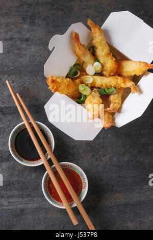 Crevettes tempura frit avec du riz et oignon de printemps dans le papier à fort-go. Servi avec des sauces, des baguettes plus vieux métal arrière-plan. Vue de dessus, de l'espace. Asian Banque D'Images