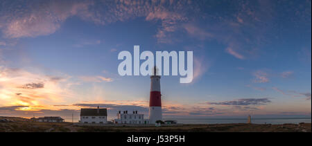 Vue panoramique de la Portland Bill lighthouse à Weymouth, Dorset, au lever du soleil, avec un ciel bleu. Il y a de petits nuages colorés. Banque D'Images