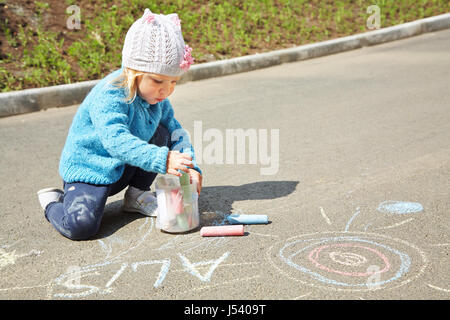 Petite fille attire la craie sur l'asphalte. enfant jouant à l'air libre à l'été Banque D'Images