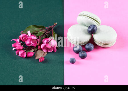 Fleurs roses à côté de macarons à la myrtille Banque D'Images