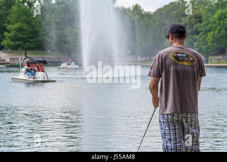 Mai 2017, Houston, Texas : Un homme poissons dans le lac McGovern dans Hermann Park avec pédalos en arrière-plan Banque D'Images