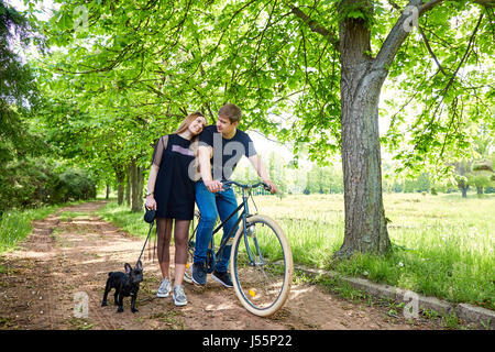 Couple aimant sur vélo avec chien dans le parc. Banque D'Images