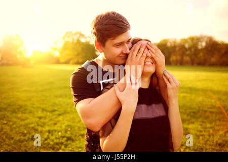 Le concept de l'amour. Un couple aimant câlins dans les rayons coucher de soleil dans la nature. Banque D'Images