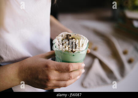 Fille est maintenant tasse de café avec de la crème de menthe verte et de décoration. Milk Shake, cocktail, frappuccino. Café Unicorn unicorn, l'alimentation. Close up, des fo Banque D'Images