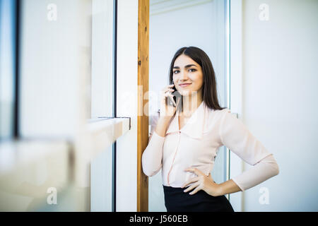 Business talk. Portrait of confident young businesswoman in suit en conversation sur le téléphone mobile et souriant Banque D'Images