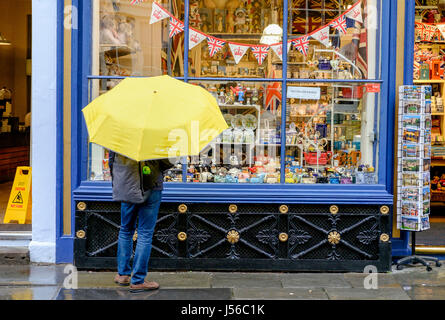 Bath, Royaume-Uni. 17 mai, 2017. Un touriste bravant la forte pluie est représenté dans l'église abbatiale Cour comme il regarde biens affichés dans une fenêtre d'une boutique de cadeaux. Credit : lynchpics/Alamy Live News Banque D'Images