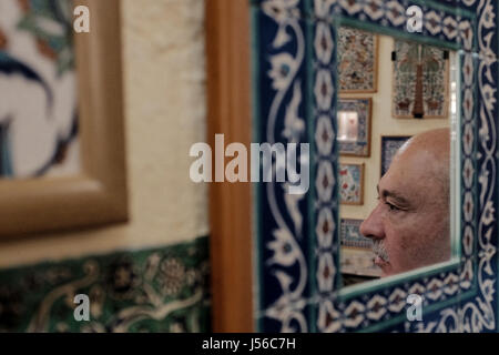 Jérusalem, Israël. 17 mai, 2017. SANDOURI HARRY, un Arménien de la famille chrétienne qui a vécu à Jérusalem pendant plus d'un siècle, se reflète dans un miroir monté par artful Armenian ceramic art travailler dans son magasin et studio dans le quartier arménien de la vieille ville de Jérusalem. Credit : Alon Nir/Alamy Live News Banque D'Images