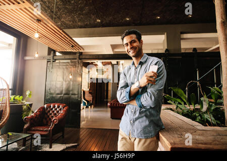 Portrait of handsome young man relaxing in modern office looking at camera et souriant. Professionnel de la création de prendre congé. Banque D'Images