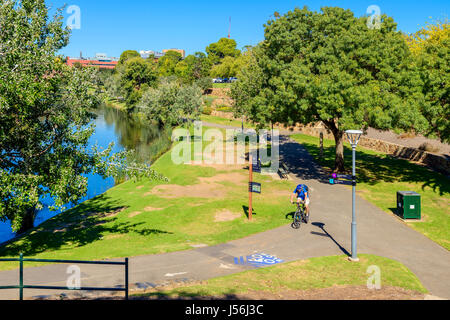 Adelaide, Australie - 14 Avril 2017 : Un homme inconnu équitation sa bicyclette le long de la rivière Torrens, piste cyclable dans North Adelaide sur un jour lumineux Banque D'Images