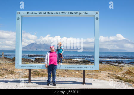 L'île de Robben Island, AFRIQUE DU SUD, 18 Décembre 2016 : heureux petit garçon et grand-père ayant une photo prise au célèbre Cadre Bleu sur Robben Island, où se Banque D'Images