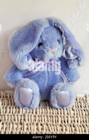 Purple lapin en peluche douce assis sur panier en osier Banque D'Images