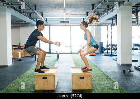 Jeune couple fit l'exercice dans la salle de sport, faisant fort sauts. Banque D'Images