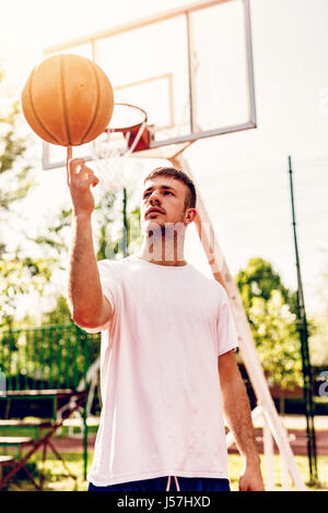 Jeune joueur de basket-ball de rue montrant ses compétences. Il bille sur le doigt. Banque D'Images