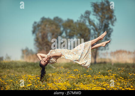 Fille flottant dans l'apesanteur sur la prairie de pissenlits. Banque D'Images