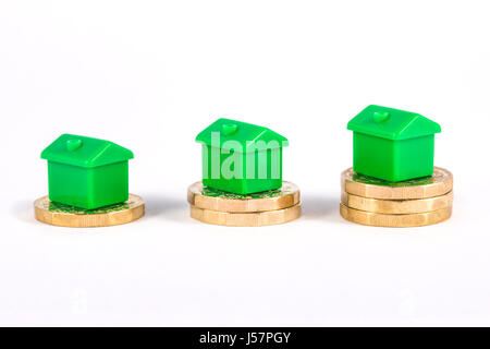 Maisons vertes assis sur des piles de pièces de monnaie, sur un fond blanc. Banque D'Images