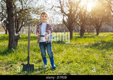 Heureux petit enfant qui pose pour photo dans jardin Banque D'Images
