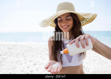 Smiling woman pouring cream sur palm at beach Banque D'Images