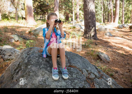 Curieux girl looking through binoculars dans la forêt Banque D'Images