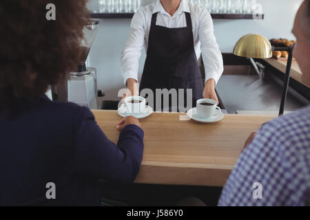 Mid section of waiter serving coffee au client au comptoir dans le Banque D'Images