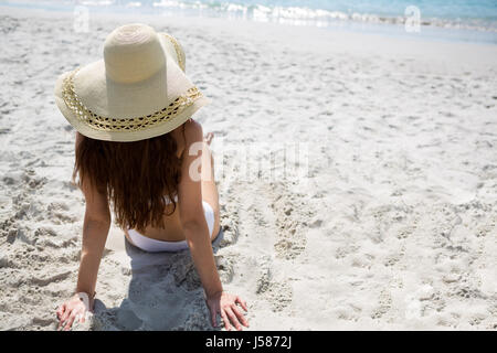 Portrait de femme portant chapeau de soleil tout en vous relaxant à la plage Banque D'Images