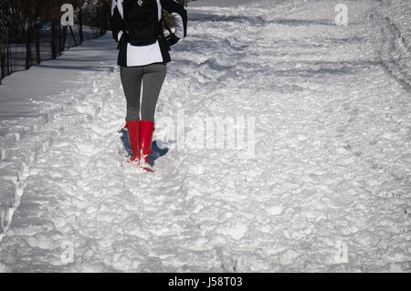 Fille avec des bottes de pluie rouge marche dans la neige Banque D'Images